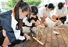 「弓切り式」の道具で火をおこす柏原高の生徒たち＝丹波市春日町黒井