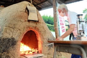 「最古の登り窯」から火を採る井上幸子さん＝丹波篠山市今田町上立杭