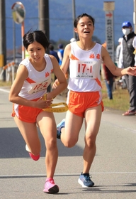 女子・柏原の１区檜田菜奈選手（右）からたすきを受け取る２区中尾友香主将＝丹波篠山市内（撮影・吉田敦史）