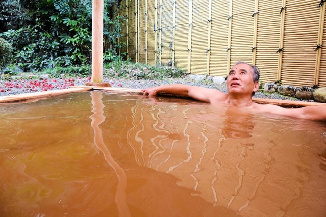 茶褐色の温泉につかり、リラックスする観光客＝「国領温泉　助七」