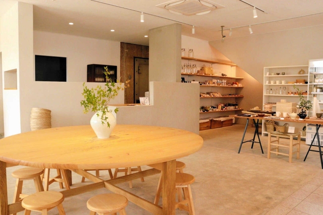 店内の中心に置かれたヒノキの大きな円卓。奥には全国から集めた「食」に関連した商品が並ぶ＝丹波篠山市古市、素滋食堂