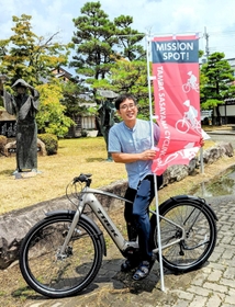 コース設定をした自転車店経営者、村上大輔さん。ピンク色の「ＭＩＳＳＩＯＮ　ＳＰＯＴ！（ミッションスポット）」ののぼりがある市内の協力店には、自転車スタンドや空気入れポンプが設置されている＝丹波篠山市役所
