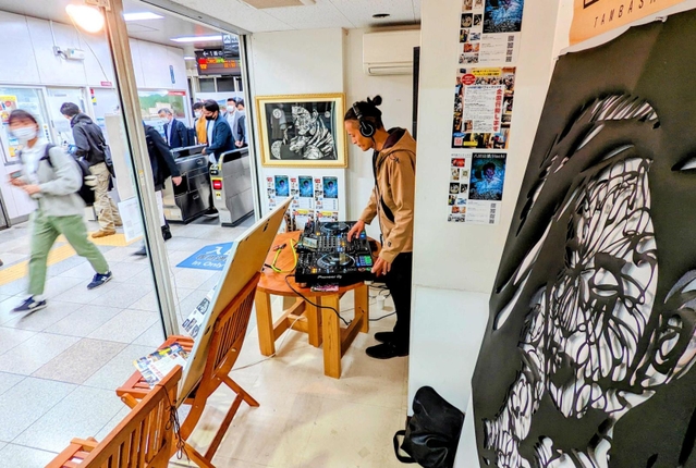 駅改札のすぐ横に設けられたブースでプレーするＤＪ。手前は公開制作で完成した切り絵アート＝ＪＲ篠山口駅