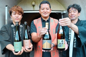 三宝ダムトンネル前で新商品の貯蔵酒を手にする（左から）山名洋一朗社長、西山周三社長、荻野弘之専務＝丹波市春日町上三井庄