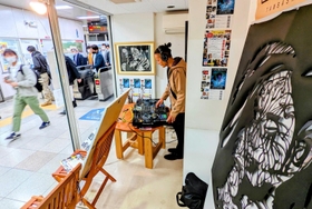 駅改札のすぐ横に設けられたブースでプレーするＤＪ。手前は公開制作で完成した切り絵アート＝ＪＲ篠山口駅