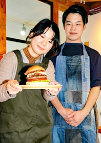 コーラポークチーズバーガーを提供する池内さん夫妻。高さは１０センチ以上＝丹波市氷上町絹山