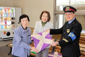 手編みの座布団を寄贈した矢村冬子さん（左）とＪＲ谷川駅の東村善夫駅長（右）ら＝ＪＲ谷川駅
