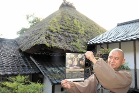 本堂のかやぶき屋根と渡辺正規住職。屋根には雑草が生い茂っている＝達身寺