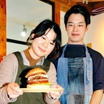 コーラポークチーズバーガーを提供する池内さん夫妻。高さは１０センチ以上＝丹波市氷上町絹山