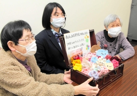 細見春美さん（左）と前田信枝さんから、卒業生を代表し、編み物を受け取る芦田日和さん＝氷上西高校