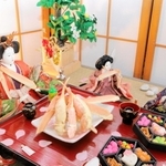 料理旅館「黒井屋」の名物「六角弁当」などを頬張ろうとする人形＝丹波市青垣町佐治