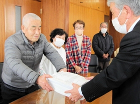 ごみ袋の半額化に賛同する署名を垣内廣明議長（右）に渡す寺田昭一さん＝丹波市氷上町成松
