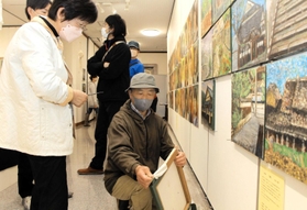 かつて柏原高校の生徒たちが描いた絵を、本人や家族に返す荒木孝典さん＝植野記念美術館