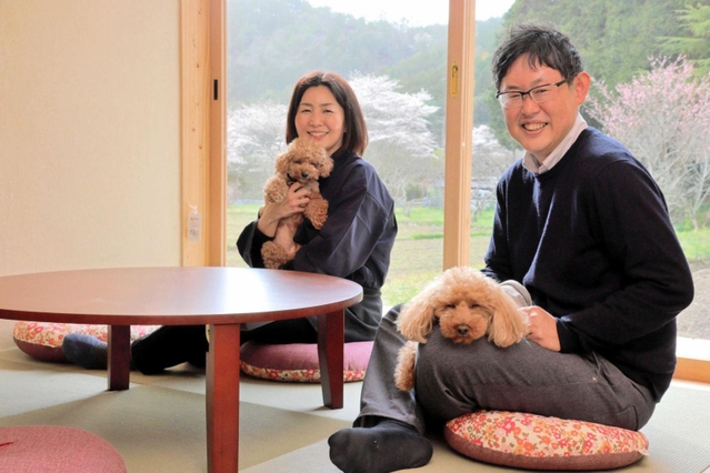 「里山ホテル　かねのね丹波」の部屋で、愛犬を抱く笹西真理さんと哲矢さん＝丹波市柏原町上小倉