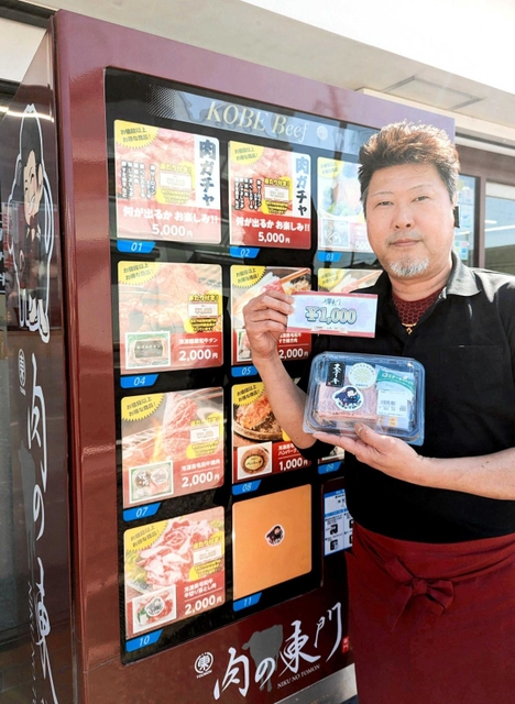 「肉ガチャ」がある冷凍牛肉自販機の横で、ステーキ肉や商品券を手にする東門昭喜社長＝丹波篠山市西新町