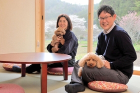 「里山ホテル　かねのね丹波」の部屋で、愛犬を抱く笹西真理さんと哲矢さん＝丹波市柏原町上小倉