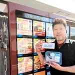 「肉ガチャ」がある冷凍牛肉自販機の横で、ステーキ肉や商品券を手にする東門昭喜社長＝丹波篠山市西新町