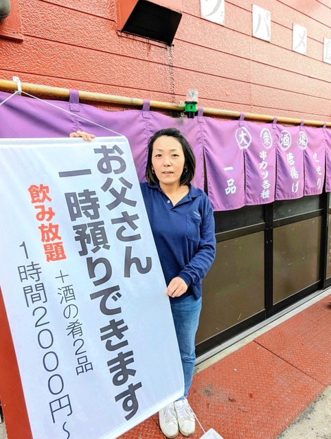 呼び文句を記した幕の横に立つ大地友代店主。観光客が撮影することもあるという＝丹波篠山市二階町