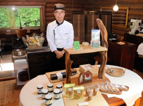 丹波篠山市産の黒豆を使った和スイーツを製造販売する「丹波樂膳」の吉本博次代表。奥が併設のカフェスペースとなっている＝丹波篠山市味間奥