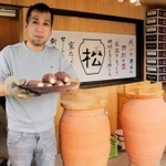 自作の壺で焼いたサツマイモを手にする「まるまつ窯」の松本格さん＝丹波篠山市今田町下立杭