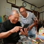 スマートフォンで注文や顧客とのやりとりに挑戦している藤原一次さん（左）＝丹波市山南町和田