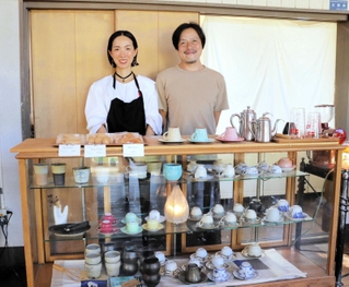 カフェ心月を営む京嶋可己悠さん、千尋さん夫妻。ガラスケースには、可己悠さんが集めたカップが並ぶ＝丹波篠山市今田町上立杭