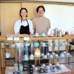 カフェ心月を営む京嶋可己悠さん、千尋さん夫妻。ガラスケースには、可己悠さんが集めたカップが並ぶ＝丹波篠山市今田町上立杭