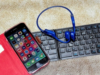 酒井さん愛用のスマートフォンと入力用キーボードと骨伝導イヤホン