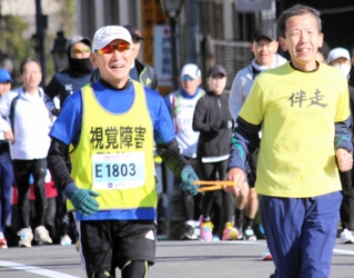 宝塚ハーフマラソン大会で伴走者とともに走る全盲ランナー、酒井智彦さん（手前左）＝２０２３年１２月２４日、宝塚大橋