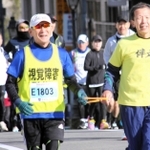 宝塚ハーフマラソン大会で伴走者とともに走る全盲ランナー、酒井智彦さん（手前左）＝２０２３年１２月２４日、宝塚大橋