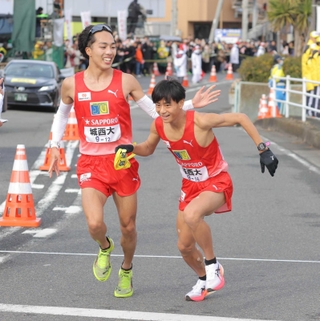 城西大７区の林晃耀選手（左）から３位でたすきを受け、走り出す８区の小田伊織選手＝神奈川県平塚市（代表撮影）