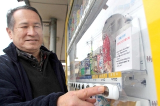 児童が作った景品を販売する自販機と余田康夫さん＝余田商店