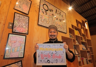 顔をテーマにしたイラストを描く足立遥紀さんと作品＝マミムメモ・ブックブック