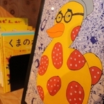 顔で画面を埋め尽くしたイラスト。本の色と合わせて作品を展示する＝マミムメモ・ブックブック