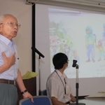 自身の戦時中の体験を基に作った紙芝居をスライドに映し、思い出を振り返る臼井邦昭さん＝丹波市春日町黒井