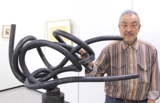 鉄製の彫刻「横たわる女」と作者のジュン・タンバこと塚脇淳さん＝植野記念美術館