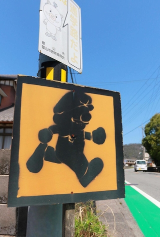 走行中の車に飛び出しへの注意を促す道路横の表示。ゲームで有名な配管工の「彼」に似たシルエットが目を引く＝丹波篠山市宮田