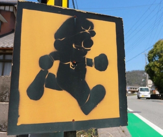 走行中の車に飛び出しへの注意を促す道路横の表示。ゲームで有名な配管工の「彼」に似たシルエットが目を引く＝丹波篠山市宮田