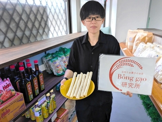 店のネームプレートとベトナムの米菓「ボンガオ」を手にする山下みかさん＝丹波篠山市東岡屋