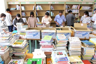 古い本を書架から抜いて整理するボランティアら＝北小学校