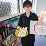 店のネームプレートとベトナムの米菓「ボンガオ」を手にする山下みかさん＝丹波篠山市東岡屋