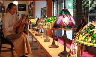 色とりどりのステンドグラスのランプが並ぶ展示会場。たて琴「ライアー」の演奏会も開かれる＝丹波篠山市今田町木津