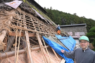 修繕が進む慧日寺本堂のかやぶき屋根東面と門脇知眞住職（右）＝丹波市山南町太田、慧日寺