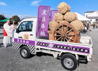 ラッピングされた軽トラック「黒豆奉納号」の安全を祈願する僧侶。荷台には、豆俵を載せた大八車が積まれた＝篠山城跡三の丸広場