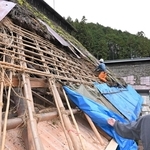 修繕が進む慧日寺本堂のかやぶき屋根東面と門脇知眞住職（右）＝丹波市山南町太田、慧日寺