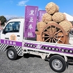 ラッピングされた軽トラック「黒豆奉納号」の安全を祈願する僧侶。荷台には、豆俵を載せた大八車が積まれた＝篠山城跡三の丸広場