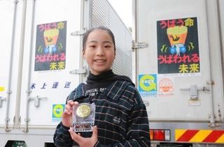 トラックにあしらわれた受賞作を背に笑顔を見せる太田花恋さん＝丹波市柏原町柏原