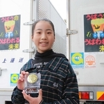 トラックにあしらわれた受賞作を背に笑顔を見せる太田花恋さん＝丹波市柏原町柏原