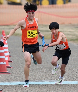 男子・丹波篠山市の２区河口航生選手（左）からたすきを受け取る３区大月拓実選手＝加古川市の加古川河川敷マラソンコース（撮影・斎藤雅志）