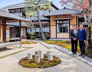住宅を改装した宿泊施設「豆家」（奥の２棟）や枯山水の庭と小田垣昇社長（左）ら＝丹波篠山市立町